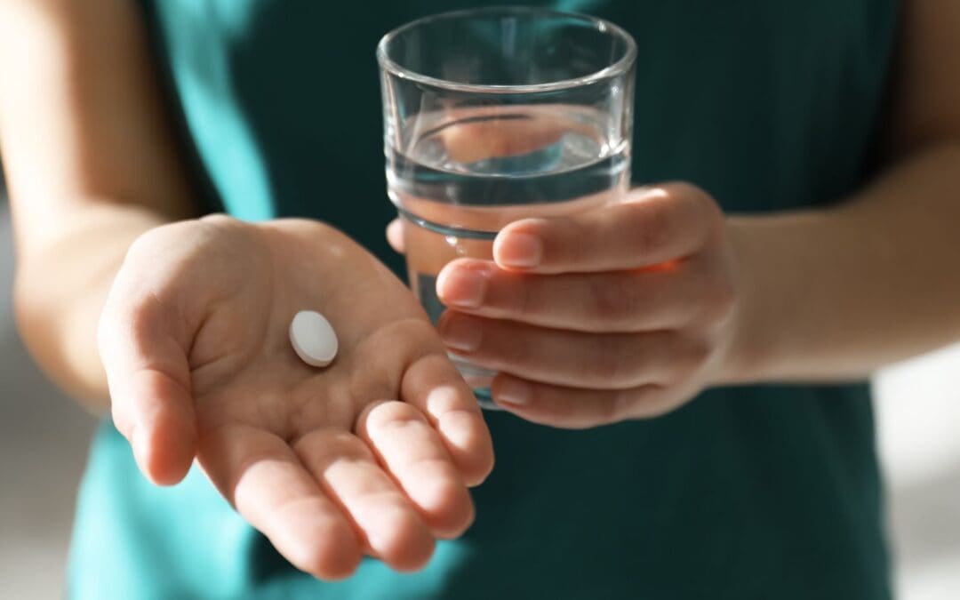 Woman holding glass of water and abortion pill
