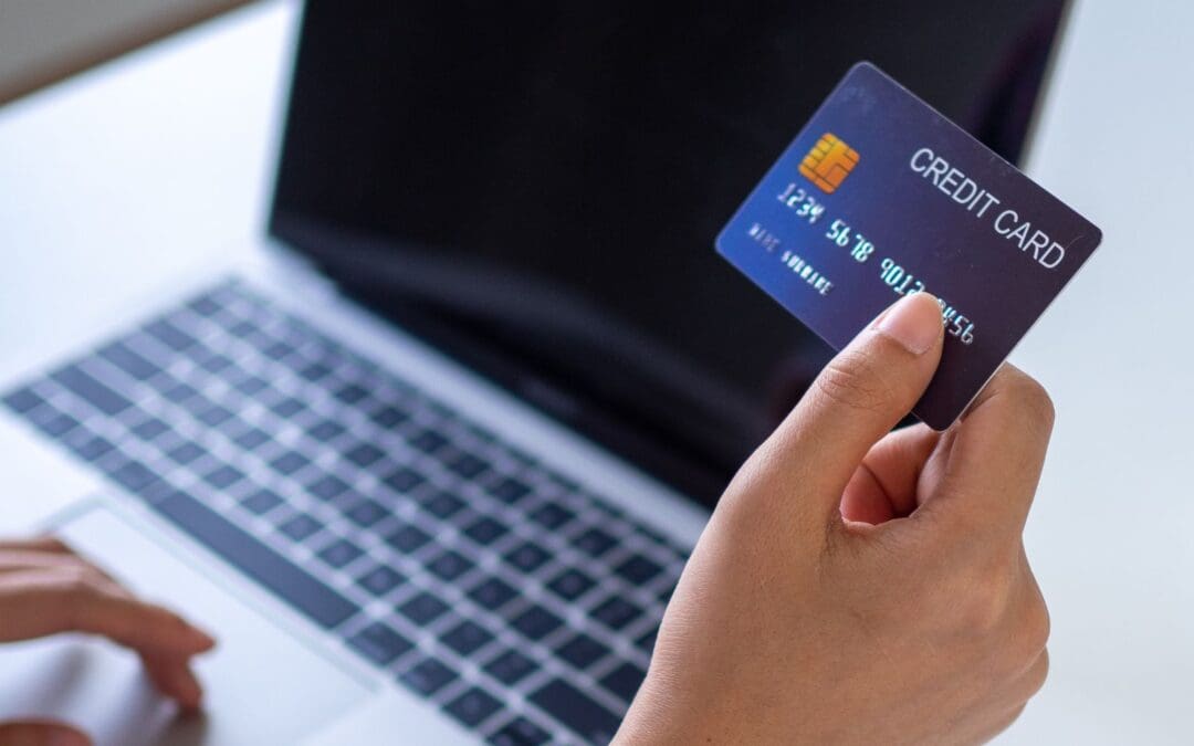 woman holding credit card facing laptop